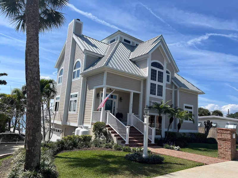 Coastal home exterior painting with metal roof and American flag by RPB Painting